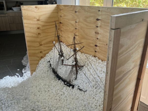 Emballage d'une maquette de bateau fragile avec caisse en bois